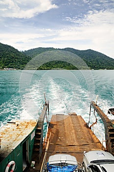 Ferry ramp and trace on the water of tropical sea behind ferry, with tropical Koh Chang island on horizon in Thailand