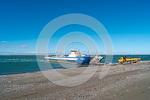 Ferry is taking cargo with cars and touristic buses at Punta Delgada through Strait of Magellan, Tierra del Fuego, Patagonia,