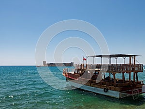 Ferryboat with turkish flag against Maiden`s castle or Kizkalesi or Deniz kalesi at the background