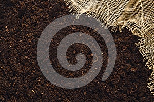 Fertile garden soil texture with jute cloth background top view