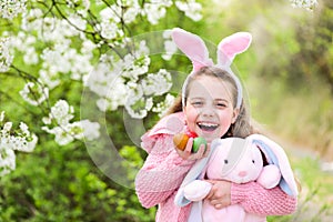 Fertility and rebirth concept Child smiling with bunny ears in garden with blossoming trees.s