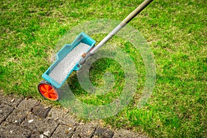 Fertilize lawn - Fertilizer spreader on green lawn photo