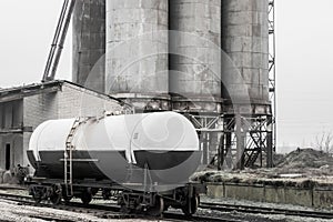 Fertilizer chemical tank on the rails of the railway industrial station against the background of old sand storage tanks at an