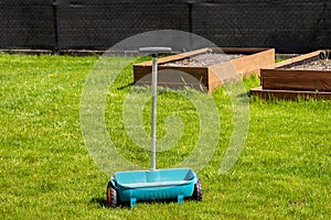 Fertilizing a young lawn with grass fertilizer in granules using a manual grass seeder.