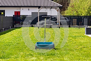 Fertilizing a young lawn with grass fertilizer in granules using a manual grass seeder.