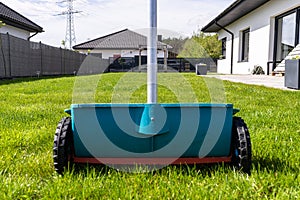 Fertilizing a young lawn with grass fertilizer in granules using a manual grass seeder.