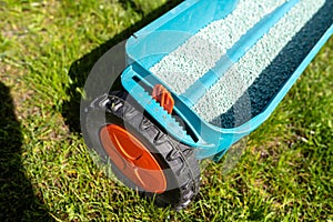 Fertilizing a young lawn with grass fertilizer in granules using a manual grass seeder.