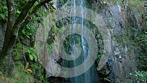 Fervenza de Augacaída Waterfall Flowing In Mossy Rock Cliff. Pullback Shot