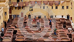Fes, Morocco - workers soak animal hides on stone vessels with dyes at Chouara Tannery in Fes el Bali.