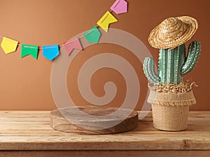Festa Junina party background with empty podium, cactus and straw hat decoration on wooden table. Brazilian summer harvest