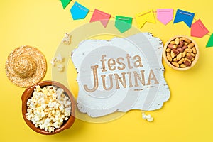 Festa Junina party background with popcorn, peanuts and wooden board. Brazilian summer harvest festival concept. Top view, flat