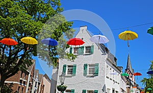 Festival day in  medieval historic lower rhine village with church, old houses, blue summer sky, colorful umbrellas - Kempen NRW