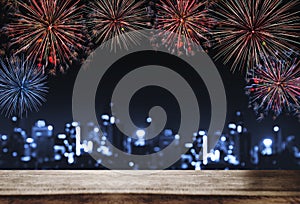 Festival fireworks at night in the city, wooden desk with Bokeh lights of building at night. For Holiday festival, New years