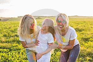 Festival of holi, friendship, happiness and holidays concept - Happy and funny girls covered in paint in green field