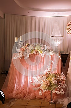 festival wedding table decoration with crystal chandeliers, golden candlestick, candles and white pink flowers and pink