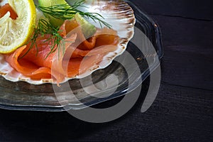 Festive appetizer, salmon in a scallop shell on a silver plate