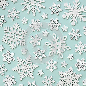 Festive arrangement of white wooden snowflakes on blue pastel background. Winter, Christmas, New Year concept