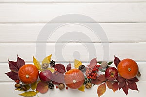 Festive autumn flat lay with pumpkins, berries and leaves on wooden background, top view