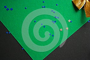 Festive backdrop with small blue confetti stars on a green and black background. New Year and Christmas theme. Template.