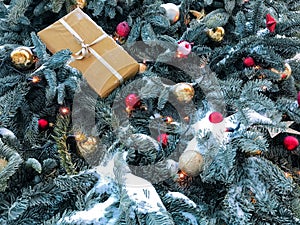 Festive background of blue Christmas tree branches covered with snow, with golden, red balls, garlands and a gift box. Copy space