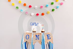 Festive background decoration for birthday celebration. Letters text one and one candle in small cupcakes for baby child birthday