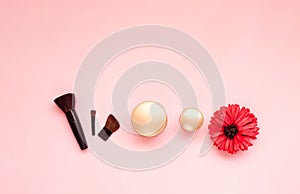 Festive background for decorative cosmetics with gerbera flower. Cosmetic brushes and shadows on pastel pink background