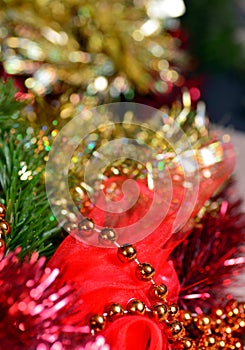 Festive background with gold and red tinsel, orange beads, green spruce branches. Vertical.