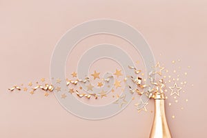 Festive background with golden champagne bottle, confetti stars, holiday decoration and party streamers in flat lay style.