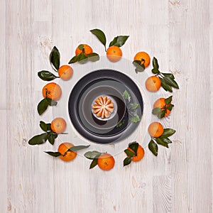 Festive background from mandarins with leaves and black plates and bowl