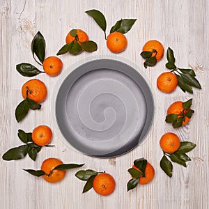 Festive background from mandarins with leaves and empty plate