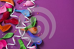 Festive background of purple material colorful balloons streamers confetti Top view flat lay copy space