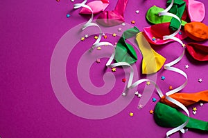 Festive background of purple material colorful balloons streamers confetti Top view flat lay copy space