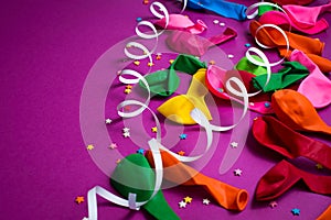 Festive background of purple material colorful balloons streamers confetti Top view flat lay copy space