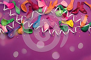 Festive background of purple material colorful balloons streamers confetti Top view flat lay copy space