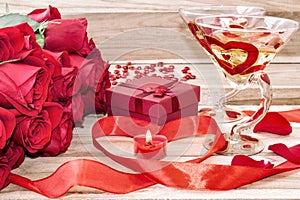 Festive background to the Valentine`s day. A bouquet of red roses, a gift box, a heart-shaped candle and a red ribbon with a heart