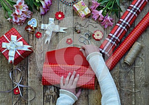 Festive background. Top view composition of woman hands wrap present for Birthday, Mother`s day, Valentine`s Day, March 8. Packed