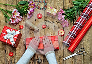 Festive background. Top view composition of woman hands wrap present for Birthday, Mothers day, Valentines Day, March 8. Packe