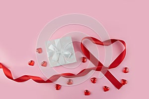 Festive background. Valentine`s Day, Mother`s Day, March 8th Box with Gift, Heart Shaped Ribbon and Hearts Next to Pink Backgrou