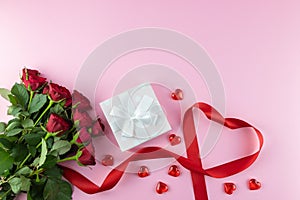 Festive background. Valentines Day, Mothers Day, 8 March. Bouquet of red roses, box with a gift, a ribbon in the shape of a