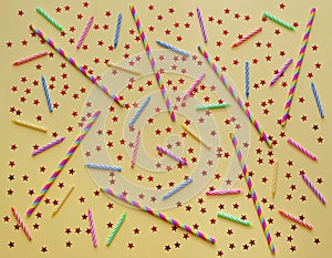 Festive birthday yellow  background with colored candles for cake, straws and stars