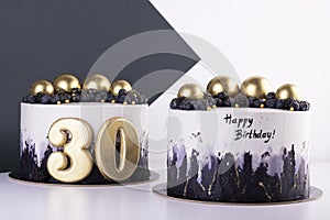 Festive black and white cakes 30 years old with golden balls and dark berries