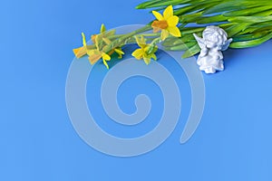 Festive blue background decorated with daffodils and a white angel. Happy Easter. Valentine's Day. The first spring