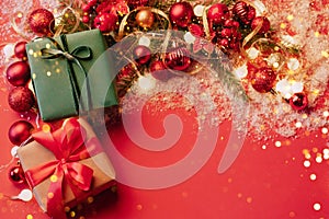 Festive boxes on a red background with Christmas toys balls a branch of fluffy fir tree, sparkles with confetti lights