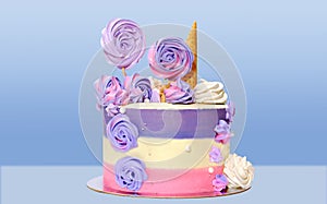 Festive cake with colored stripes of pink and purple decorated with multicolored marshmallows on a blue background for decoration