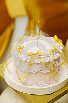Festive cake, decorated with gold bows and a candle.