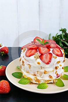 A festive cake with fresh strawberries, cream, decorated with mint leaves on a black background.