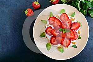 A festive cake with fresh strawberries, cream, decorated with mint leaves on a black background