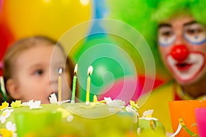Festive cake with three candles, kid with clown