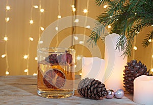 Festive card with candles and cones under a Christmas tree on a wooden table