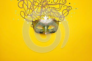 Festive Carnival mask and beads on a yellow background.